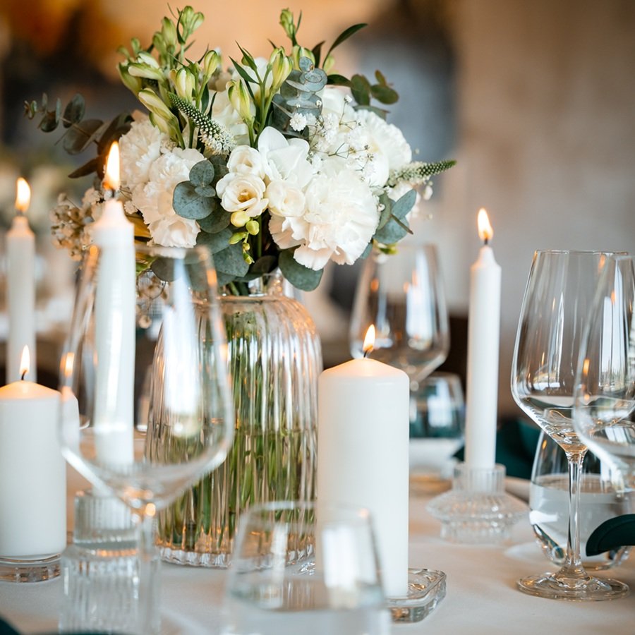 Elegante weisse Tischdekoration mit Blumen und Kerzen für eine Hochzeit