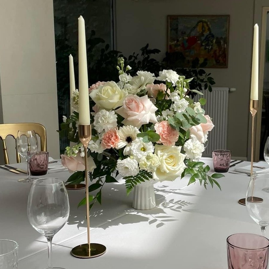 Elegantes Blumenarrangement mit weissen und pastellfarbenen Blumen auf einem Hochzeitstisch