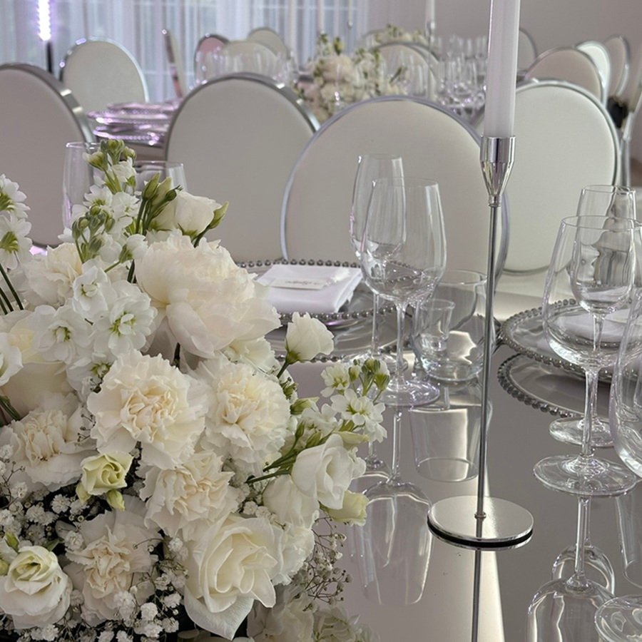 Elegante Hochzeits-Blumenkomposition mit weissen Blumen auf dem Tisch