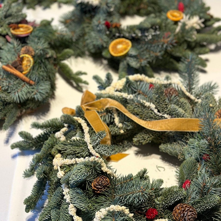 Adventskränze aus frischem Tannengrün, Zapfen, getrockneten Orangenscheiben und Zimt – handgefertigt im Floristik-Workshop.